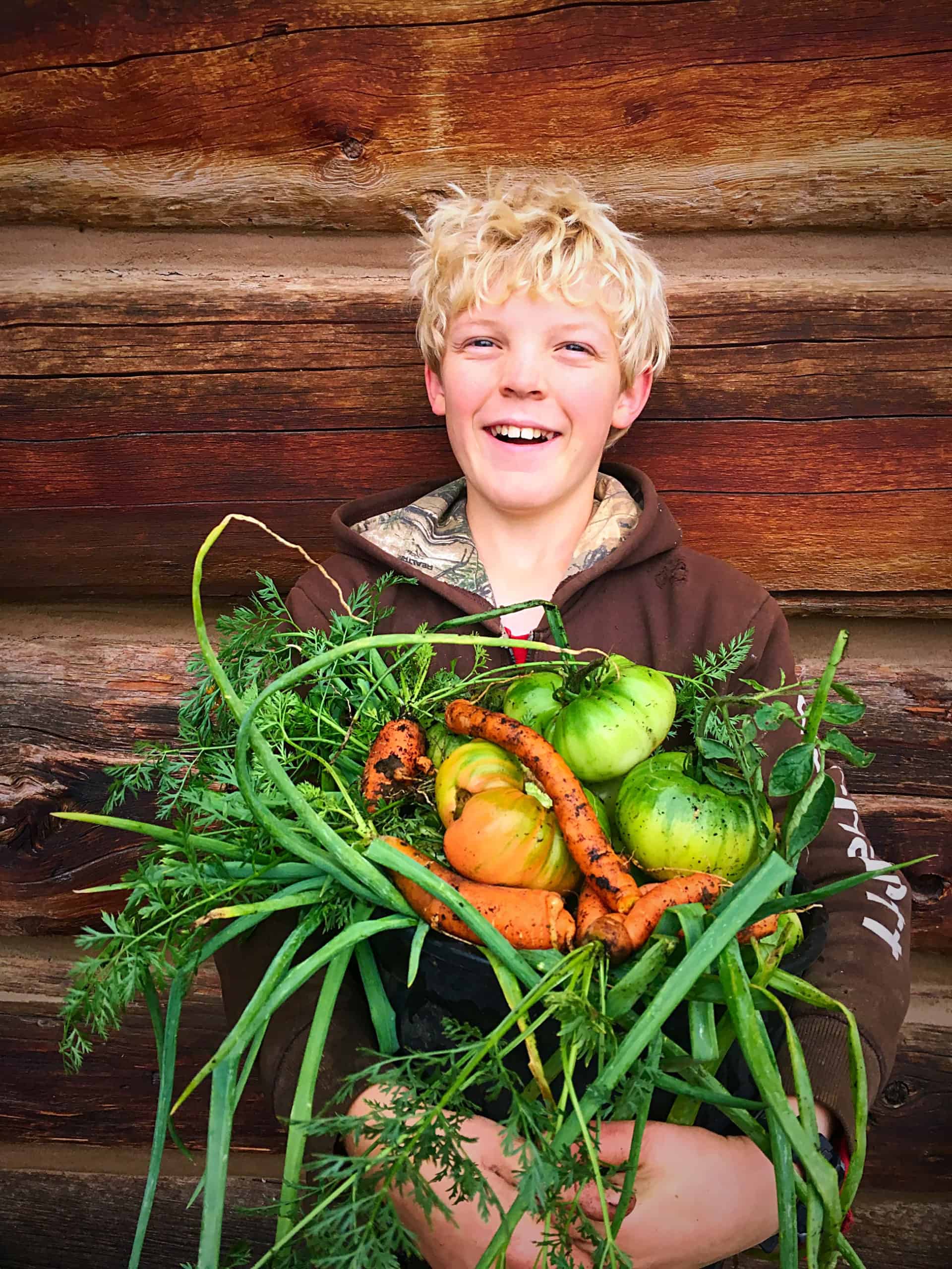 Young boy holding a basket filled with fresh produce.