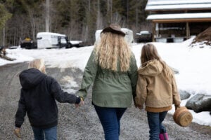 Woman and kids walking to the barn to collect eggs.