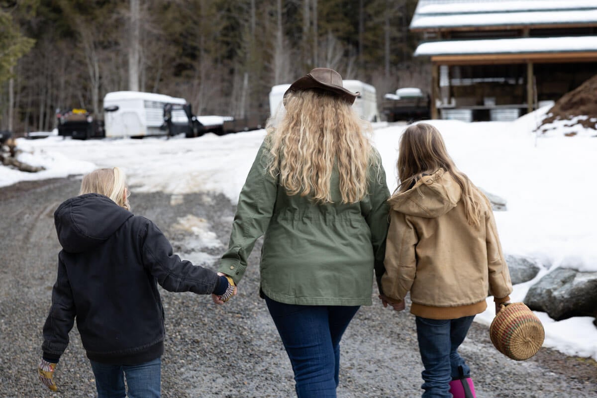 Woman and kids walking to the barn to collect eggs.