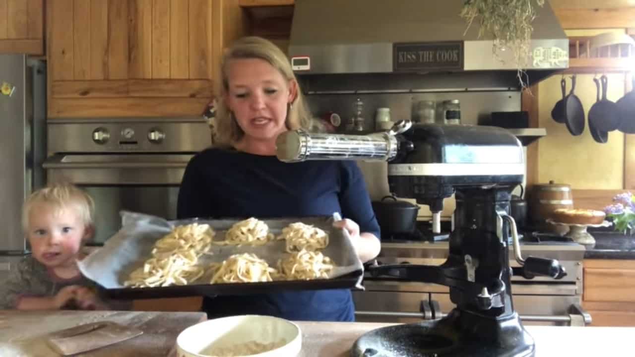 Woman holding up a pan of egg noodles in bundles.