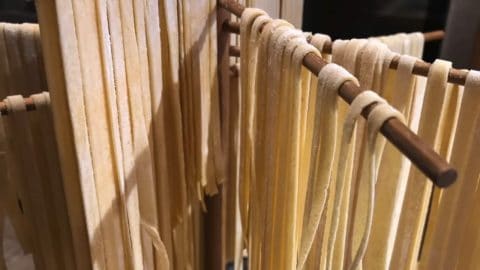 Homemade egg noodles drying on a noodle rack.