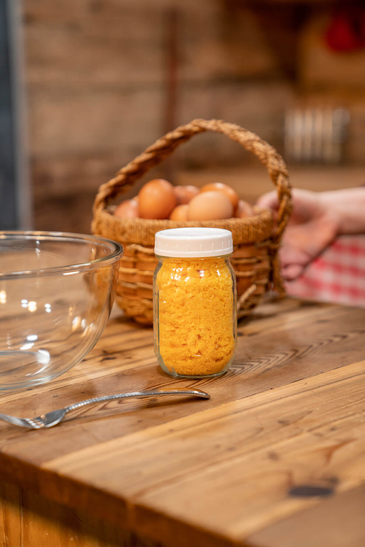 A small Mason jar with freeze dried eggs and a basket of fresh eggs.