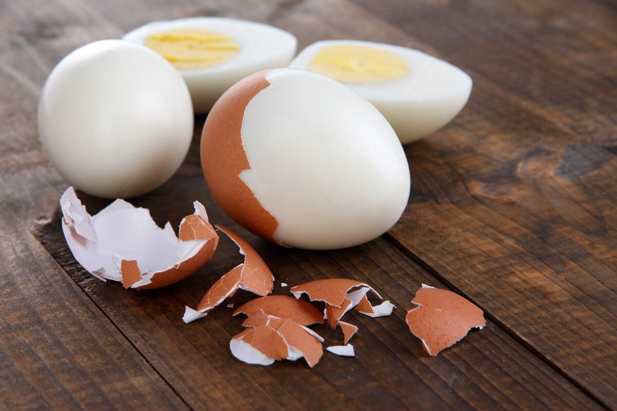 Hard boiled eggs that have been peeled on a wooden counter.