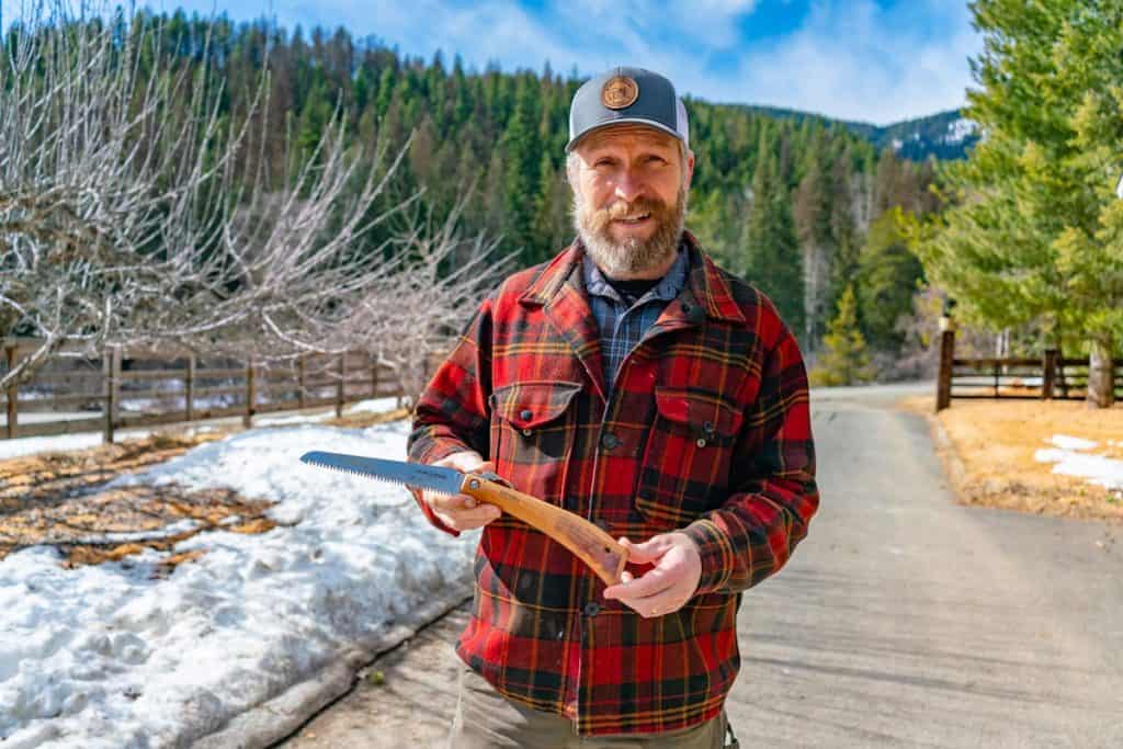 Man holding a folding pocket hand saw.