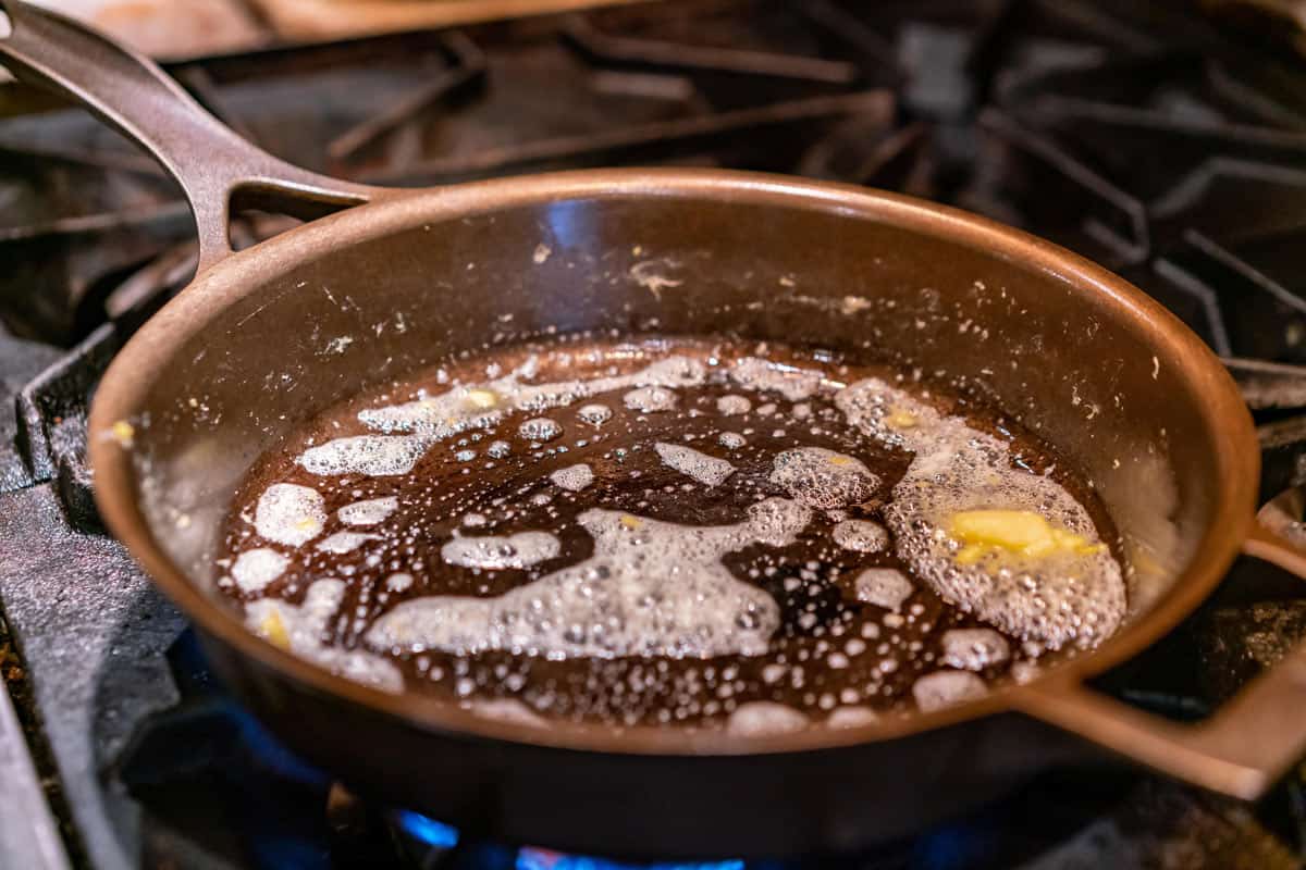 A hot cast iron pan with melted butter in it.