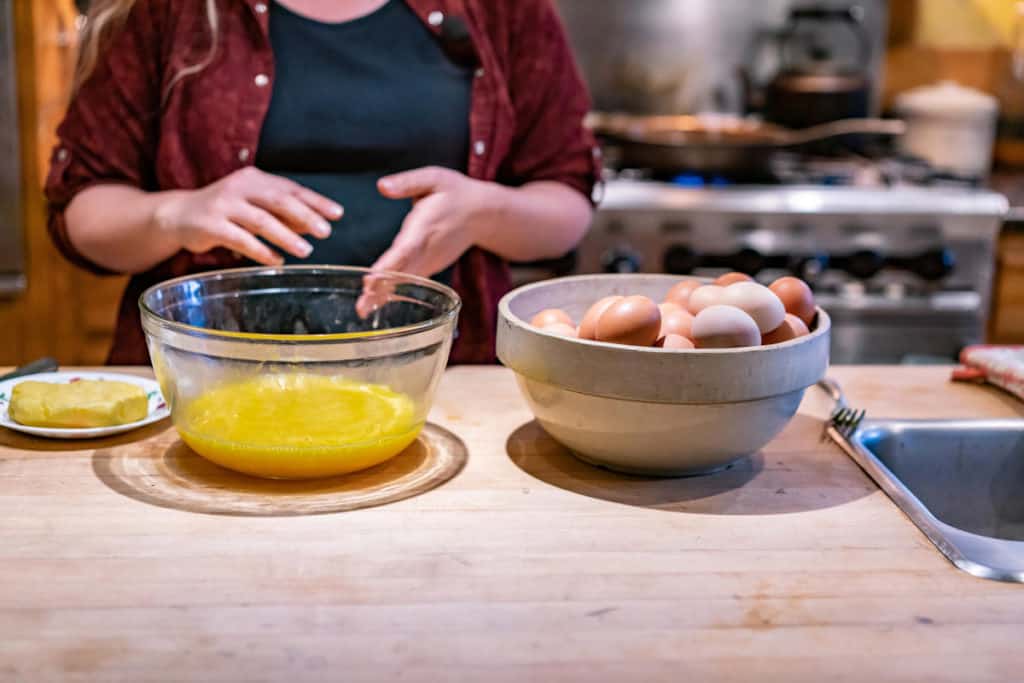 Two bowls on a kitchen counter, one with whole eggs, and one with cracked scrambled eggs.