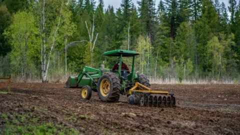 A tractor tilling a field.