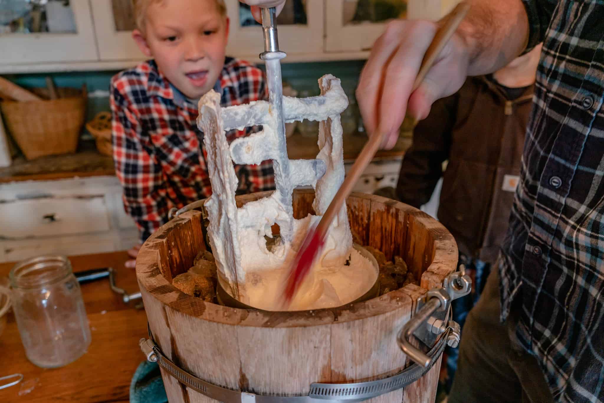 An old fashioned hand-crank ice cream maker with fresh vanilla ice cream.