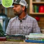 Pinterest pin with a man sitting behind a table with homesteading books on it. Text overlay says, "Best Homesteading Books".