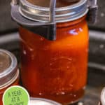 Photo of a jar of food in a water bath canner. Pinterest pin of what to preserve by month.