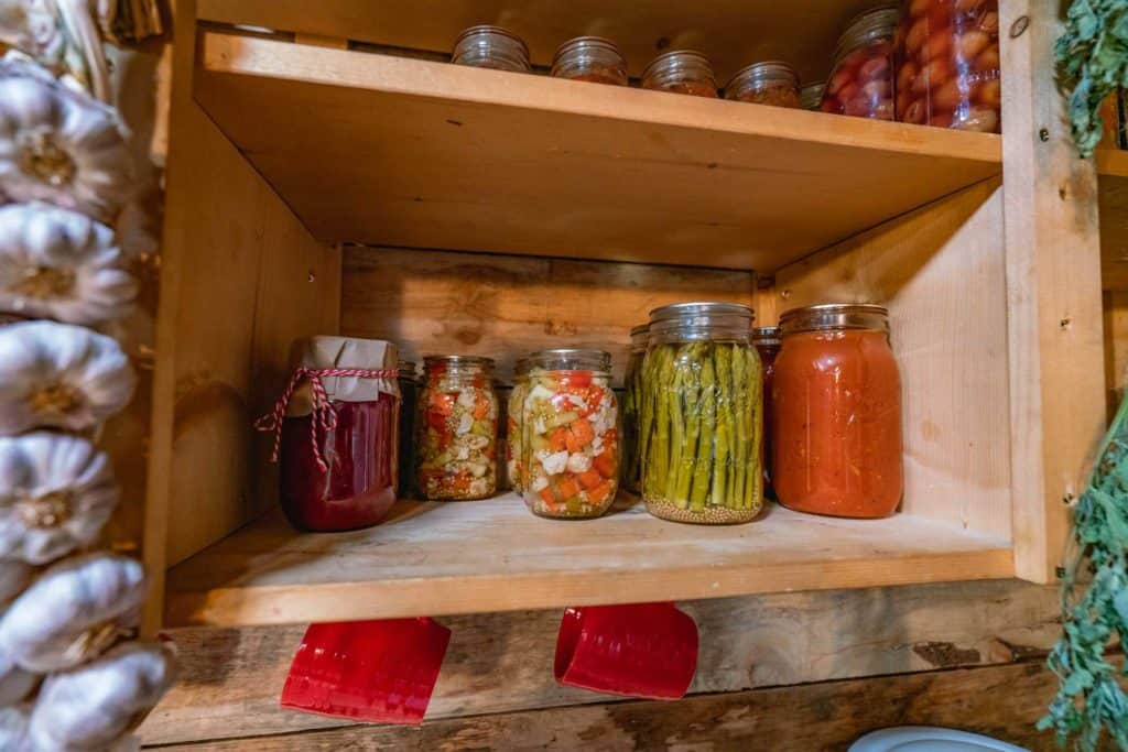 Colorful canning jars sitting on a shelf.