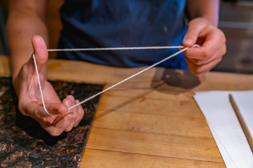 Hands showing a string tied in a large loop.