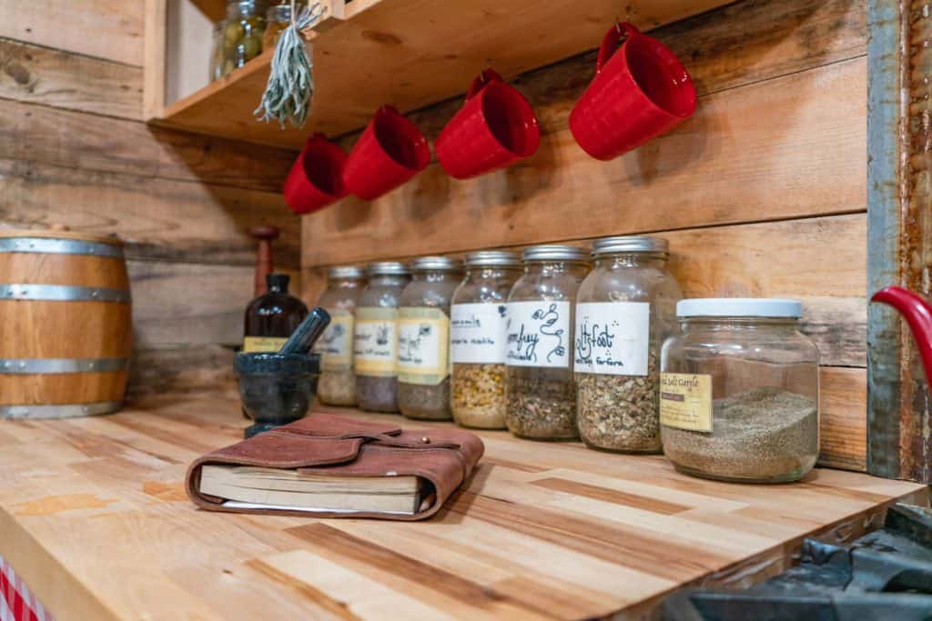 Jars of dried herbs, or mortar and pestle and a notebook sitting on a kitchen counter.