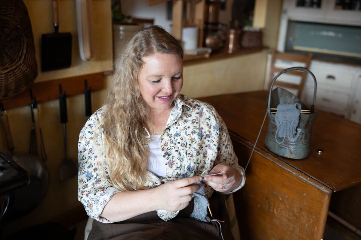 A woman sitting in a chair knitting.