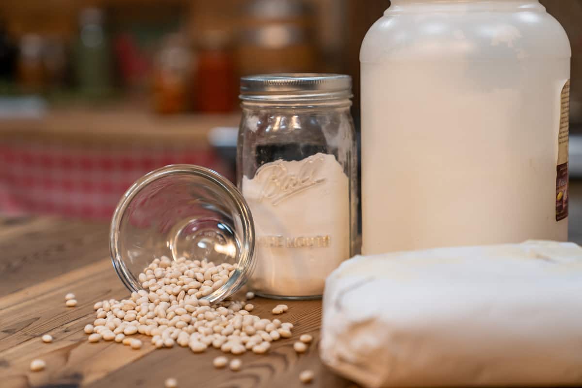 Dry beans spilling out of a jar next to some other pantry staples.