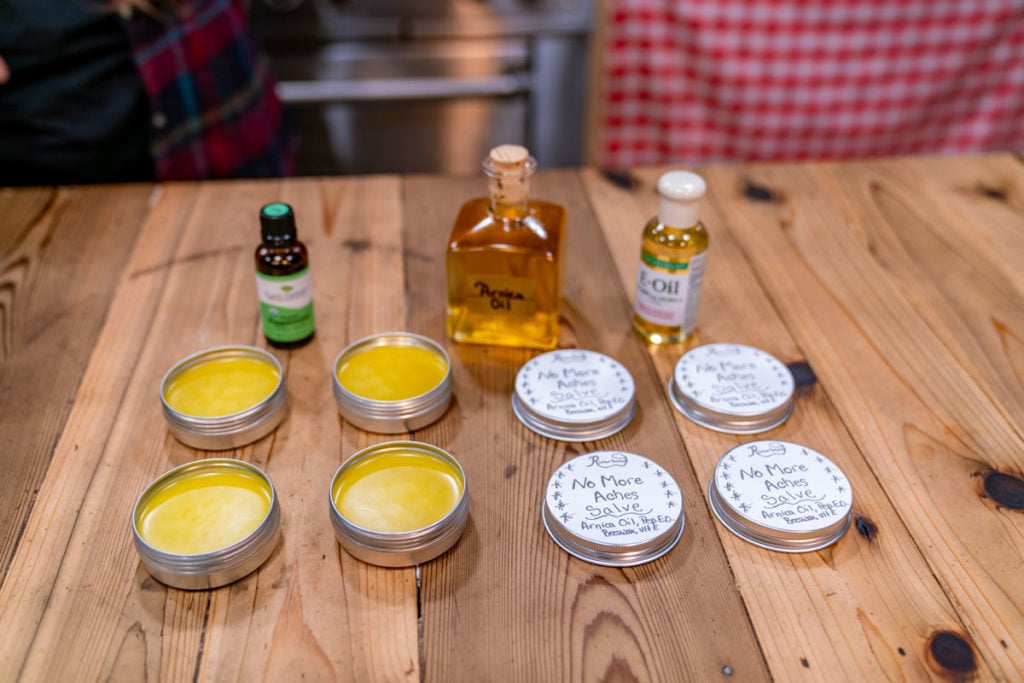 Tins of arnica salve with the ingredients laid out on a table.