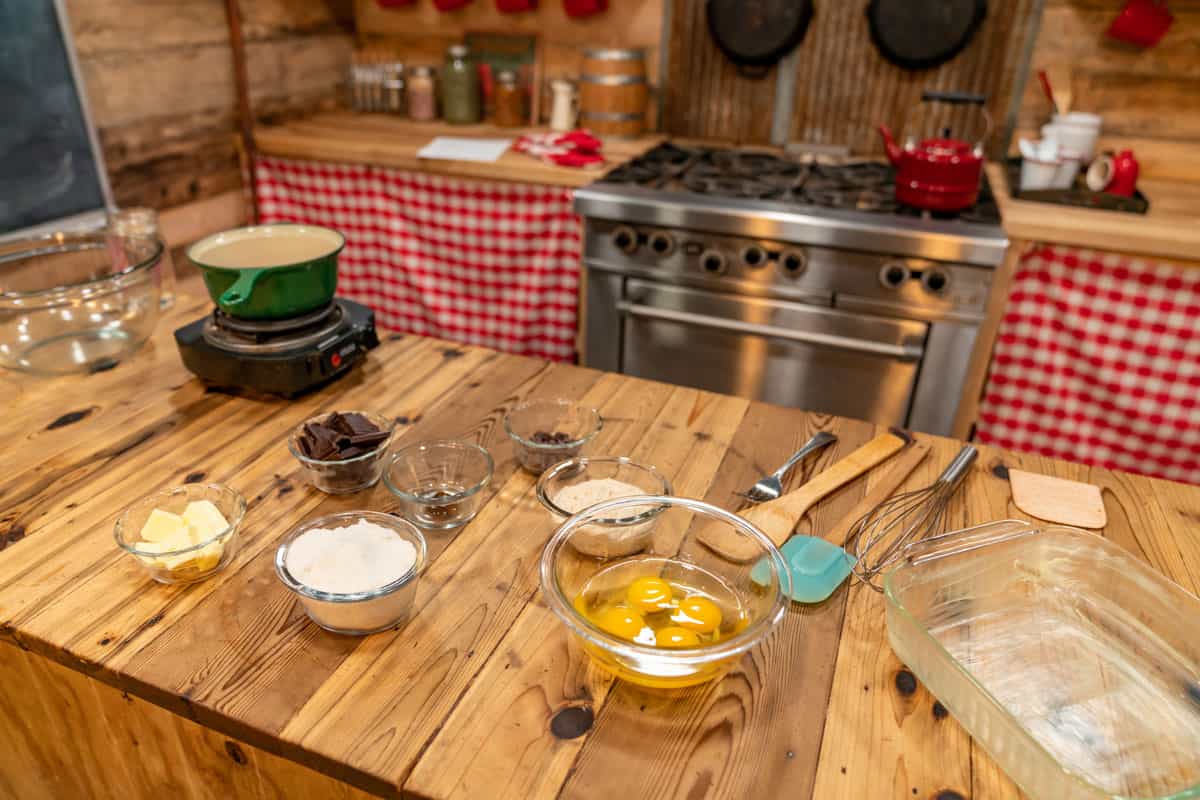 Small glass bowls filled with ingredients for sourdough brownies and a pot on a burner for a double boiler.