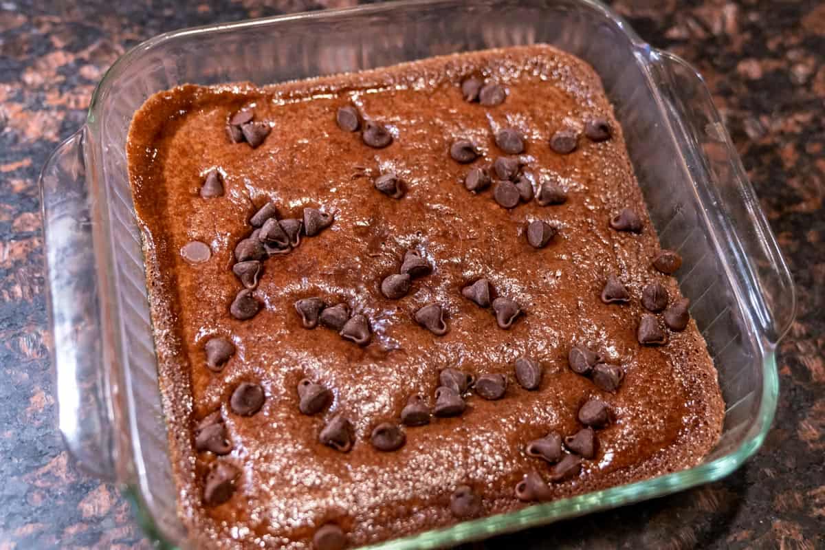 An 8x8 baking pan with sourdough brownies topped with chocolate chips.