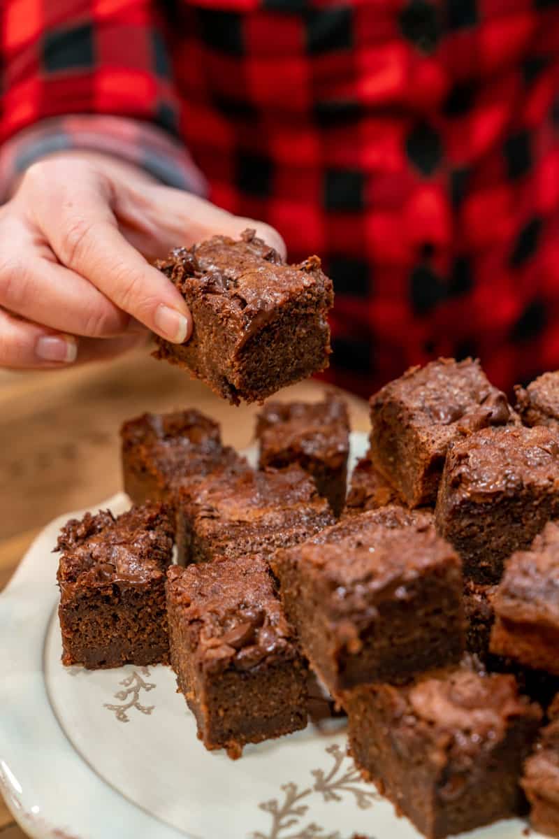 A hand picking up a sourdough brownie off a serving platter.