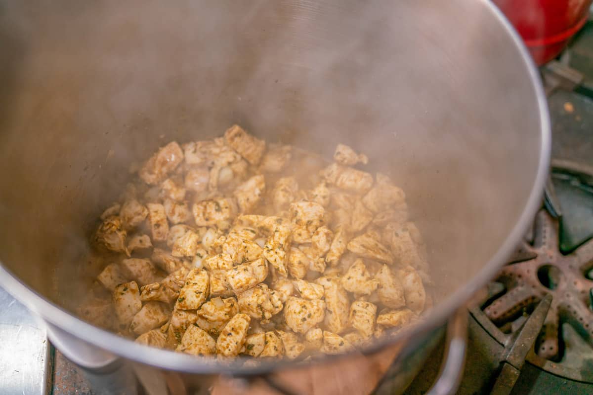 Chicken and spices cooking in a large stockpot.