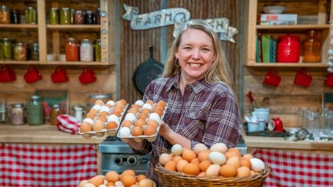 A woman standing in the kitchen with dozens of farm fresh eggs.