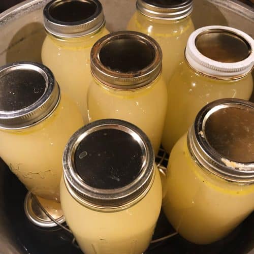 Quart jars of chicken broth inside a pressure canner.