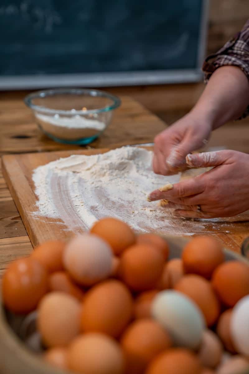 A woman mixing eggs into flour for egg noodles.