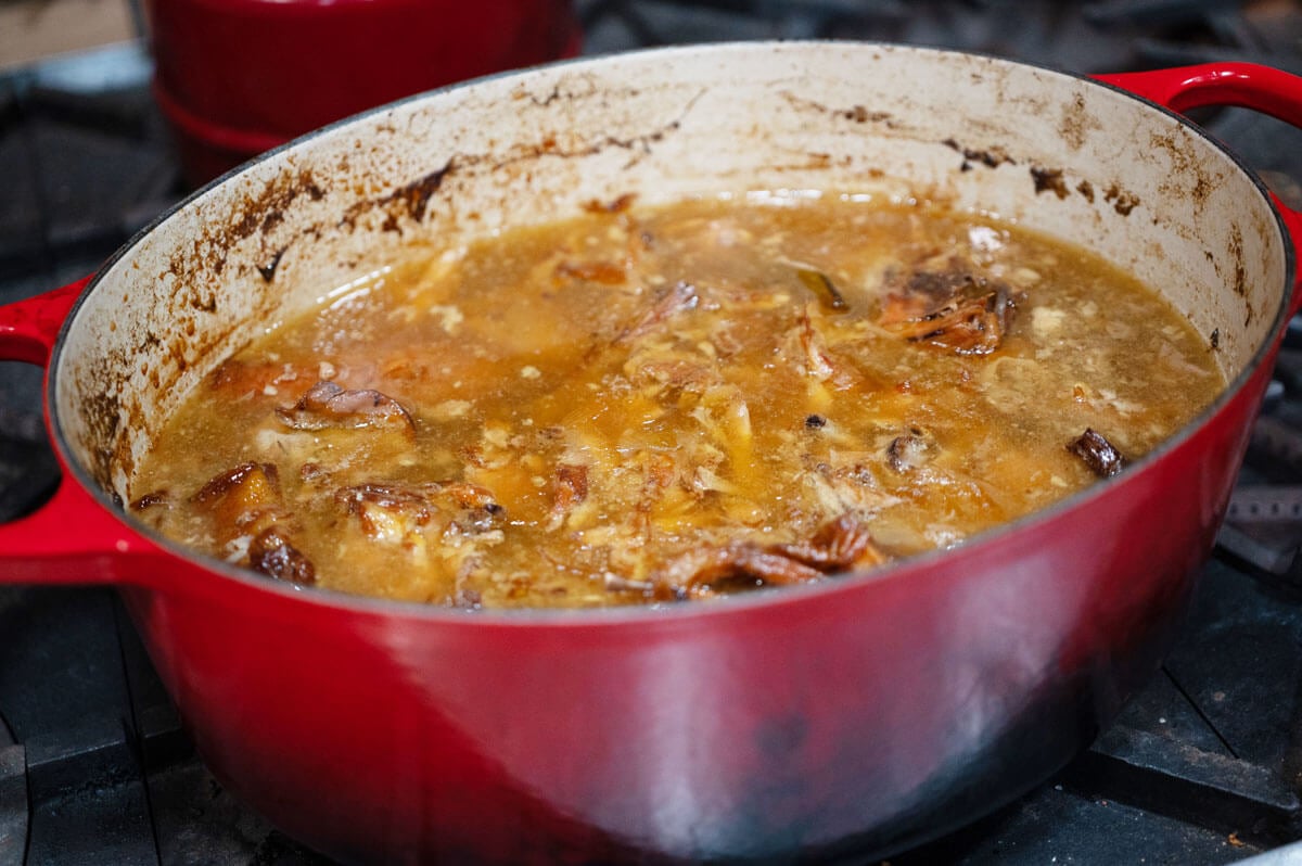 A Dutch oven filled with simmered bone broth ready to be strained.