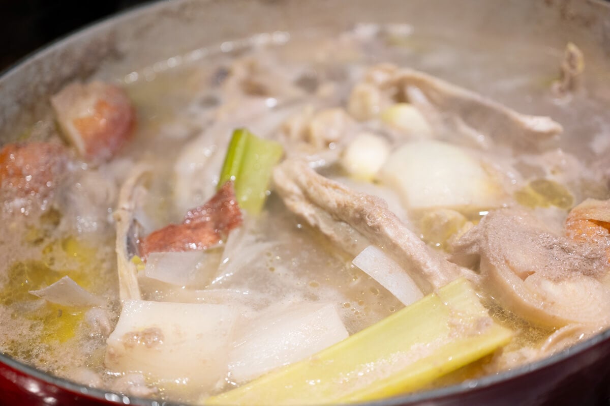 Homemade chicken bone broth simmering in a Dutch oven.