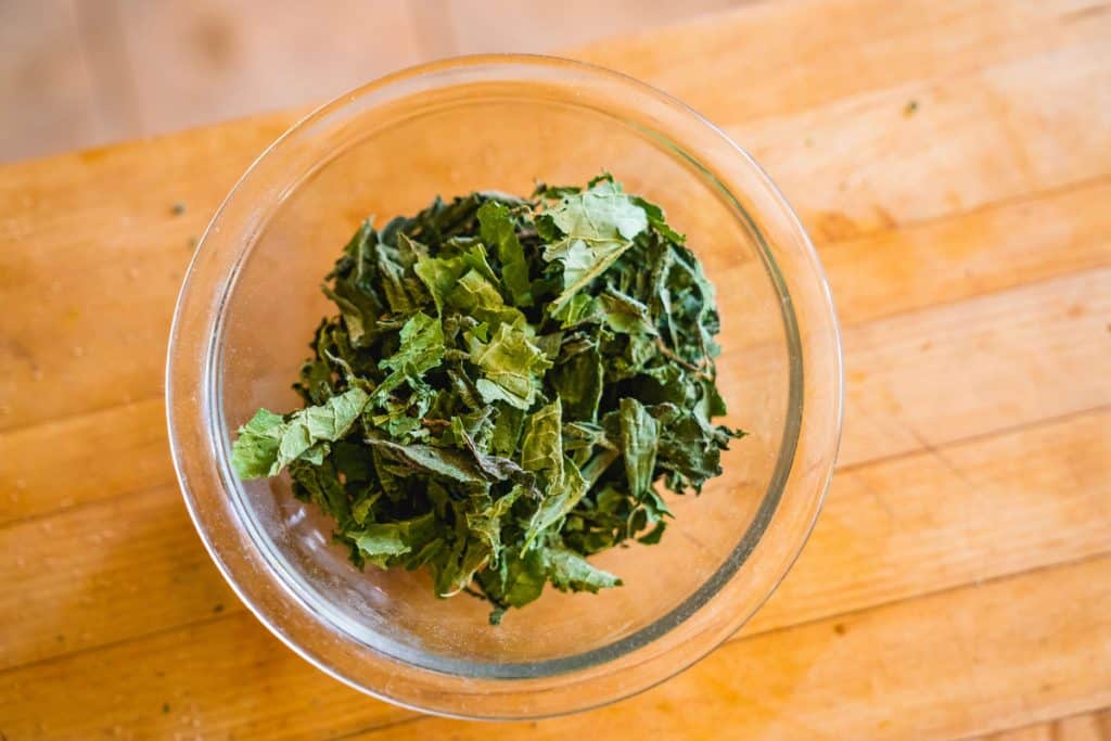 A small glass bowl filled with dried comfrey leaves.