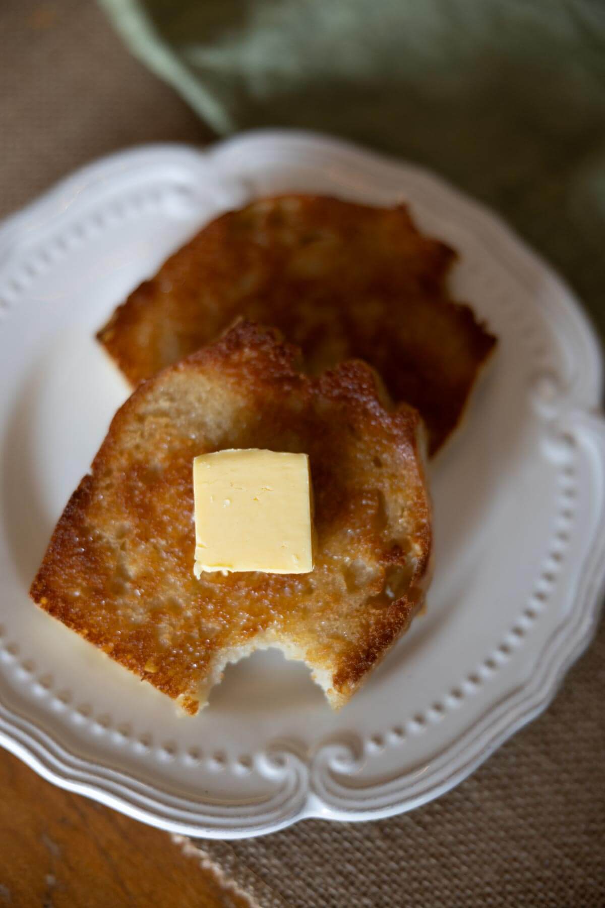 Two slices of toast on a white plate topped with a pat of butter.