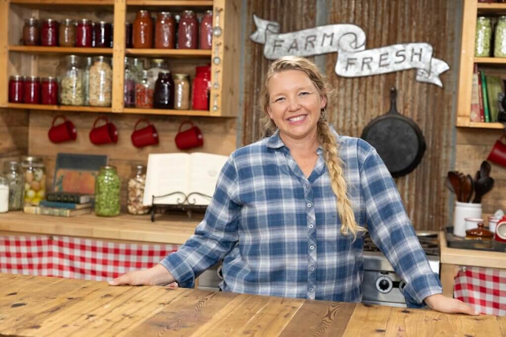 A woman standing at a butcher block in her kitchen.