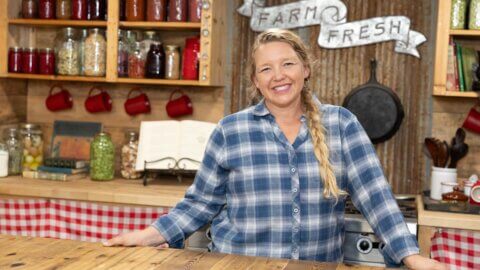 A woman standing at a butcher block in her kitchen.