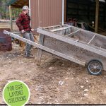 Pinterest pin on using chickens to restore the land using a mobile chicken coop. Image of a man fixing up a mobile chicken coop.