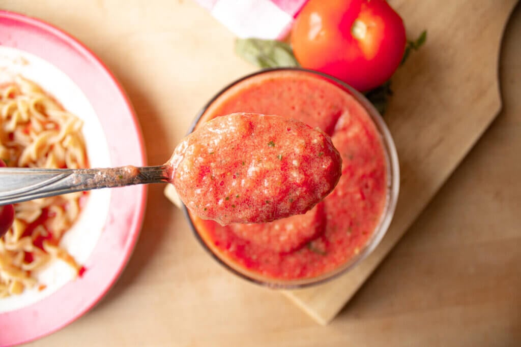 A spoon scooping out fermented tomato sauce to show the texture.