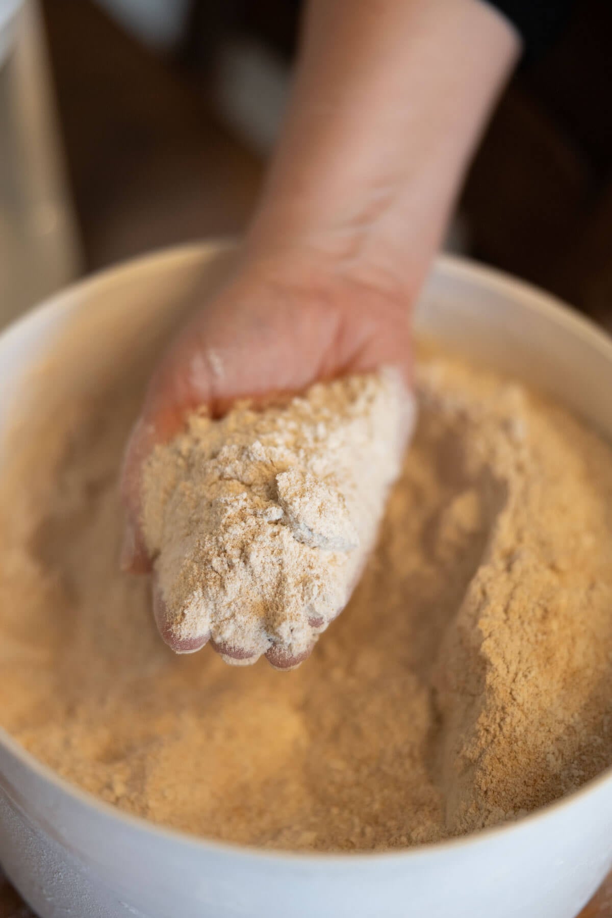A hand scooping out freshly milled flour to show the texture.