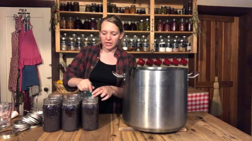 A woman getting air bubbles out of a jar filled with black beans.