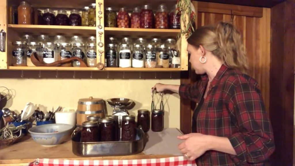 A woman lifting a jar of canned black beans and setting it on a towel lined counter.