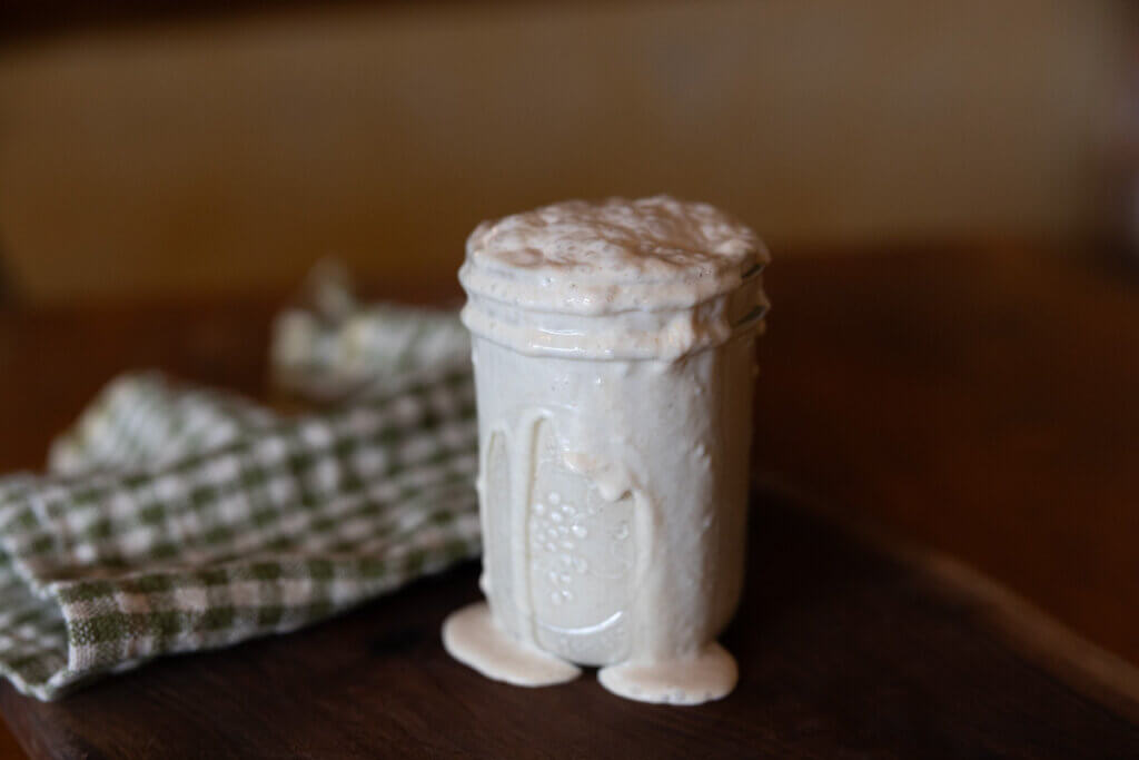 Active sourdough starter bubbling over a Mason jar.