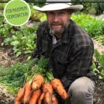 Pinterest pin for how to grow carrots from seed for maximum germination. Photo of a man holding up a giant bunch of carrots.