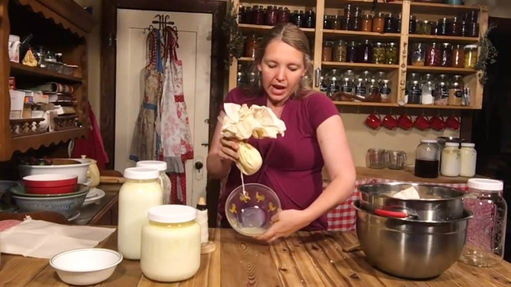 A woman showing the whey that's dripped off a bag of cultured cheese.