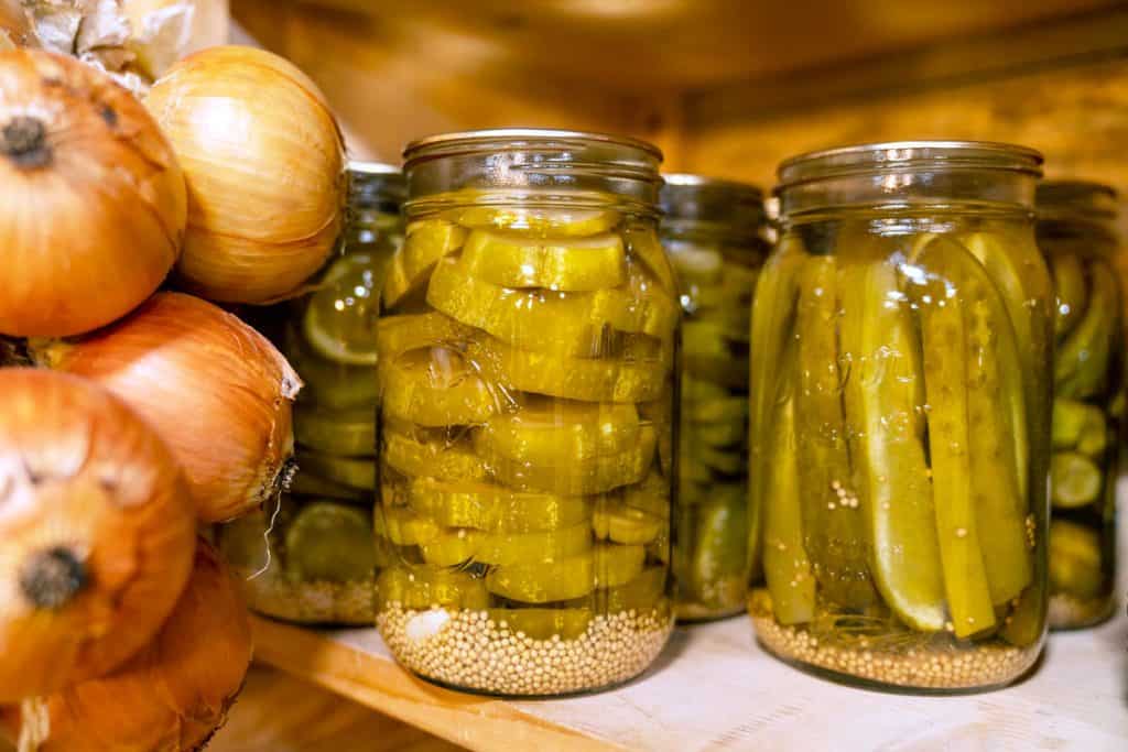 Jars of homemade pickles sitting on a pantry shelf.