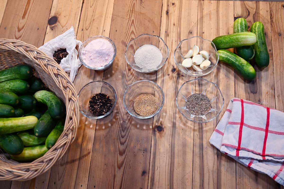 A vertical shot of pickle ingredients sitting on a wooden counter.
