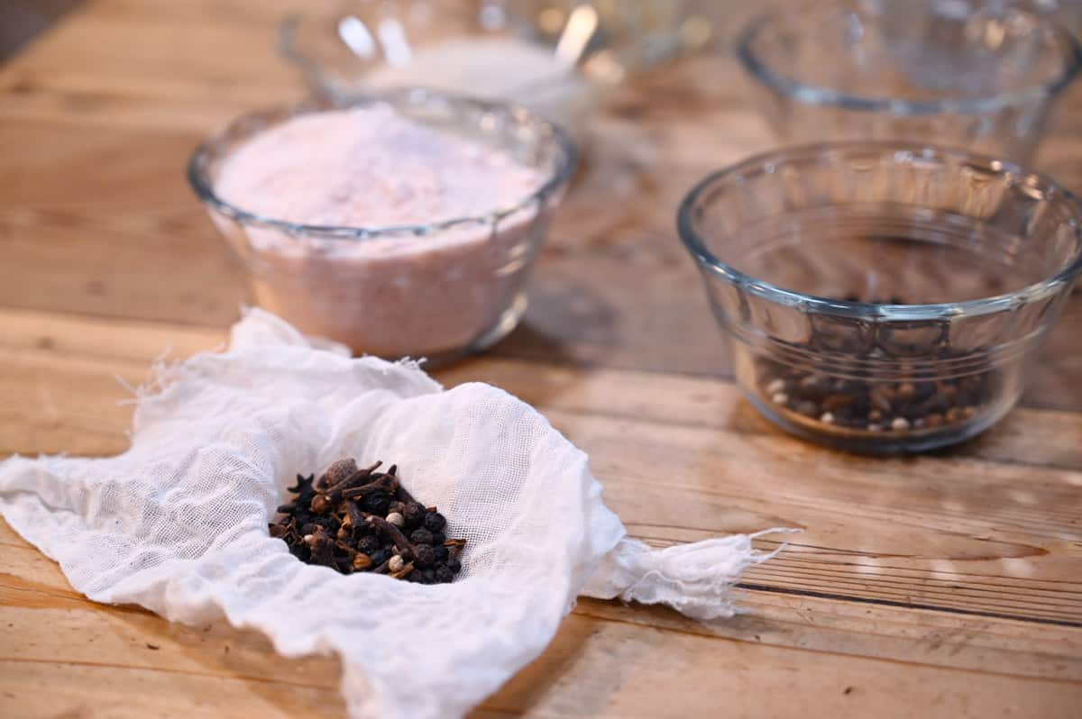 Pickle ingredients in glass bowls on a wooden counter.