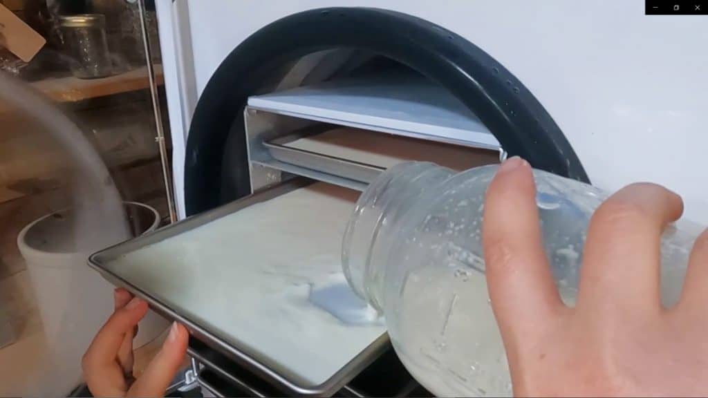 A half gallon of milk being poured into a freezer dryer tray.