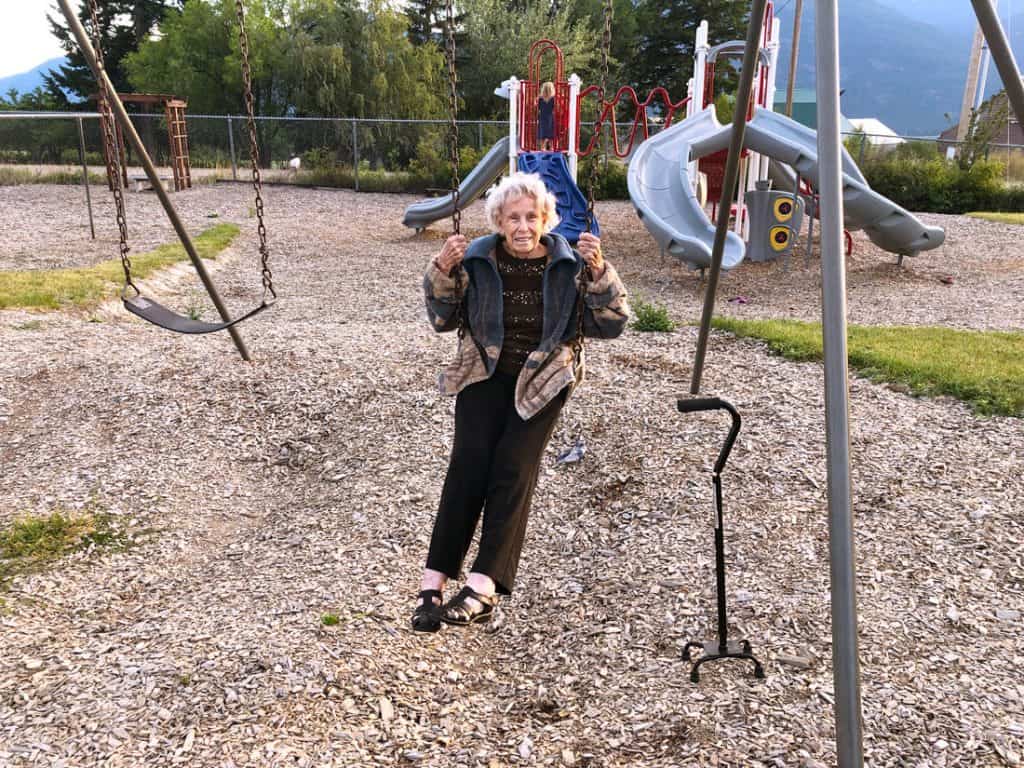 Image of an elderly woman swinging on a swingset.