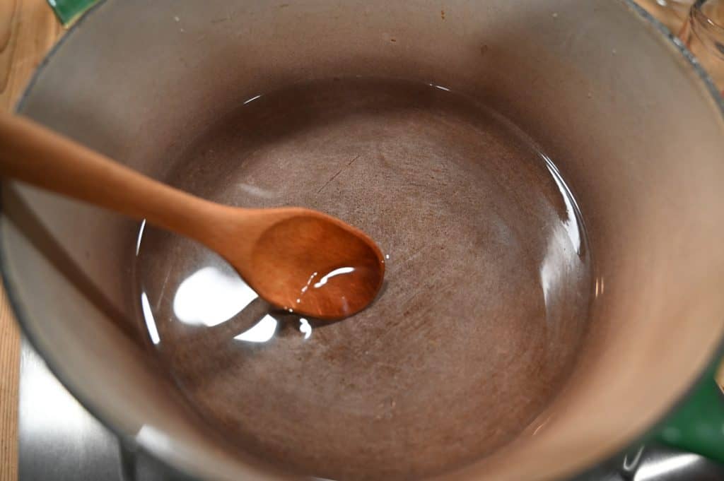Brine in a pot with a wooden spoon stirring.