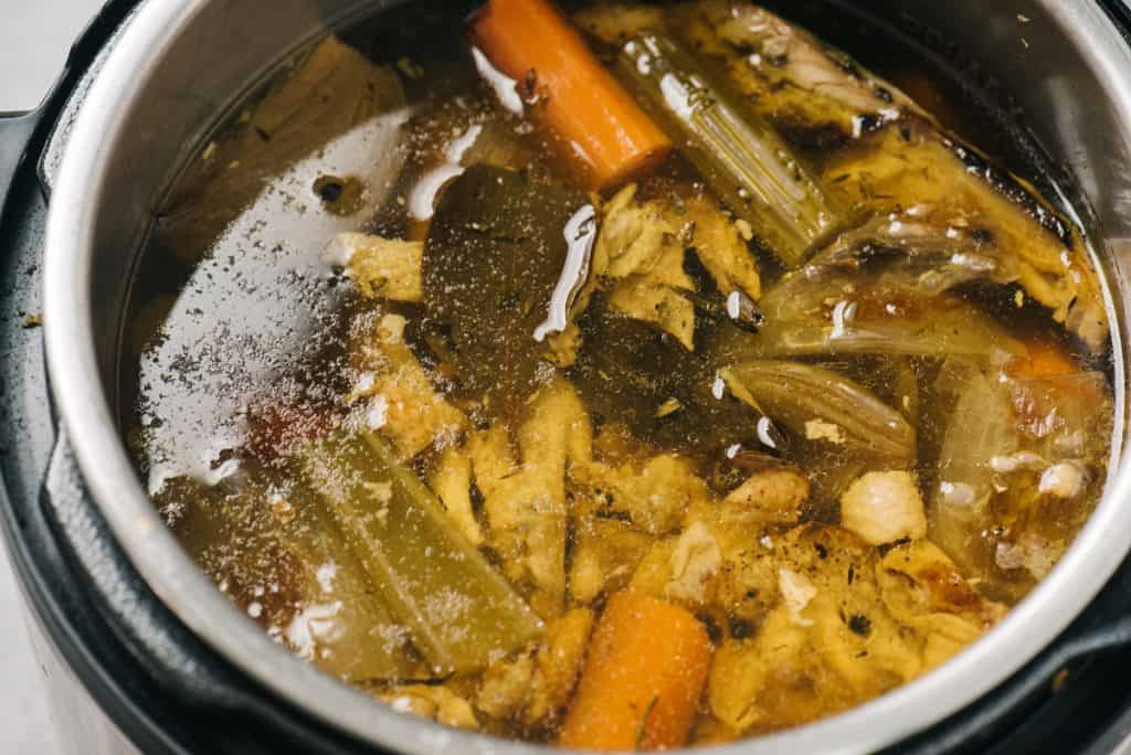 An Instant Pot filled with bone broth and ingredients.
