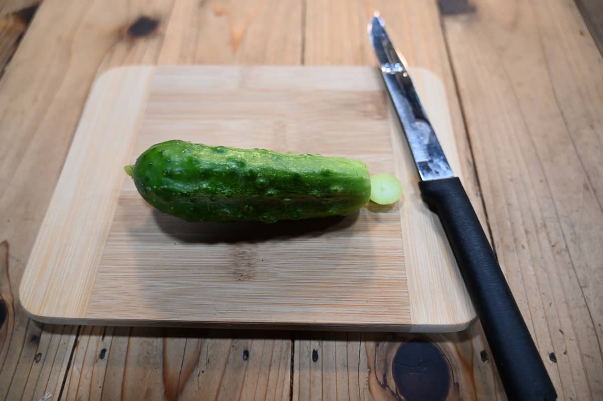 A cucumber with the end cut off on a cutting board.