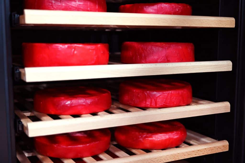 Eight waxed wheels of cheese in a cheese cave.